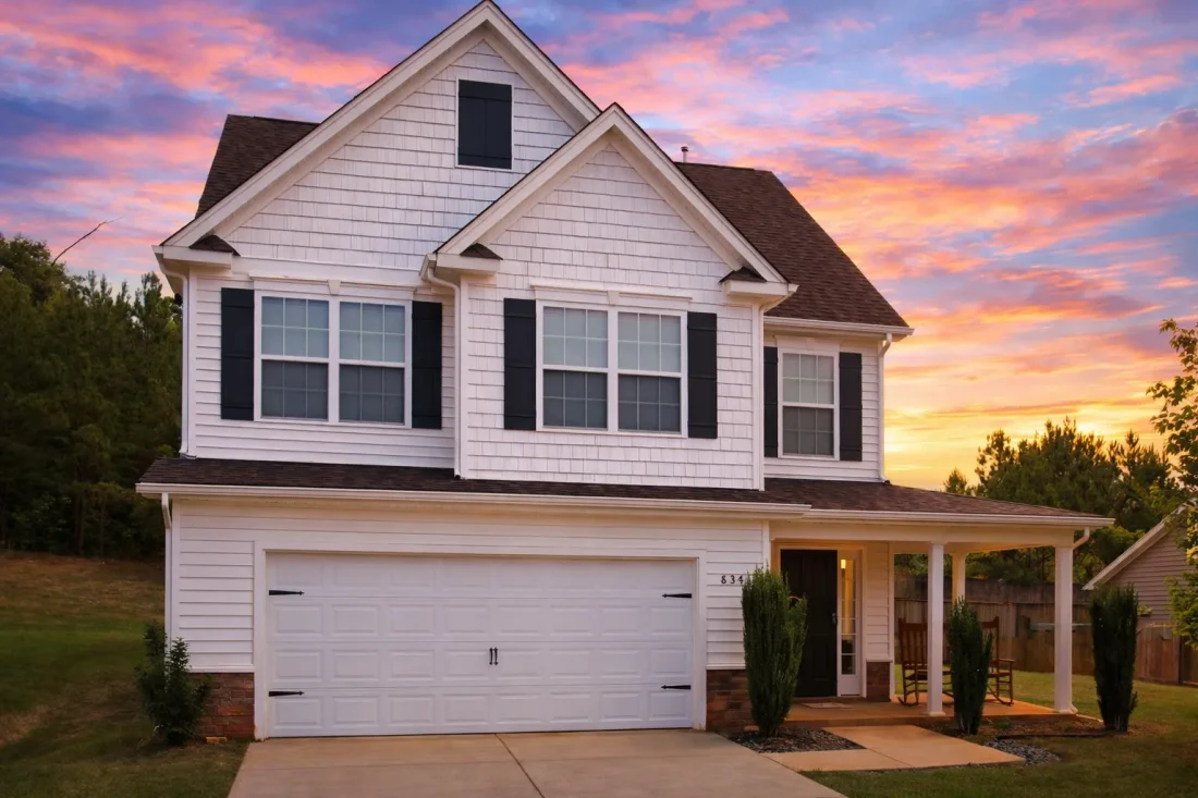 Front elevation of a Traditional Colonial style house featuring horizontal siding, stone wainscoting, black shutters, and a front-entry porch