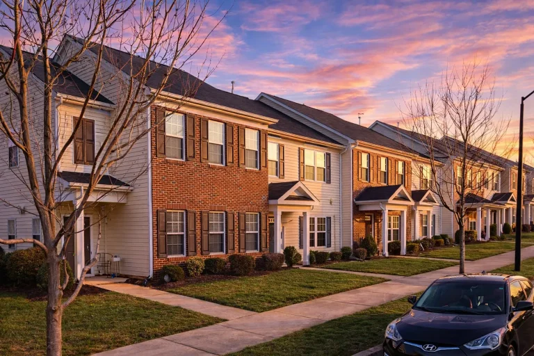 Front elevation of a Traditional Colonial style townhome featuring horizontal siding, classic symmetry, and clean multi-unit architectural detailing