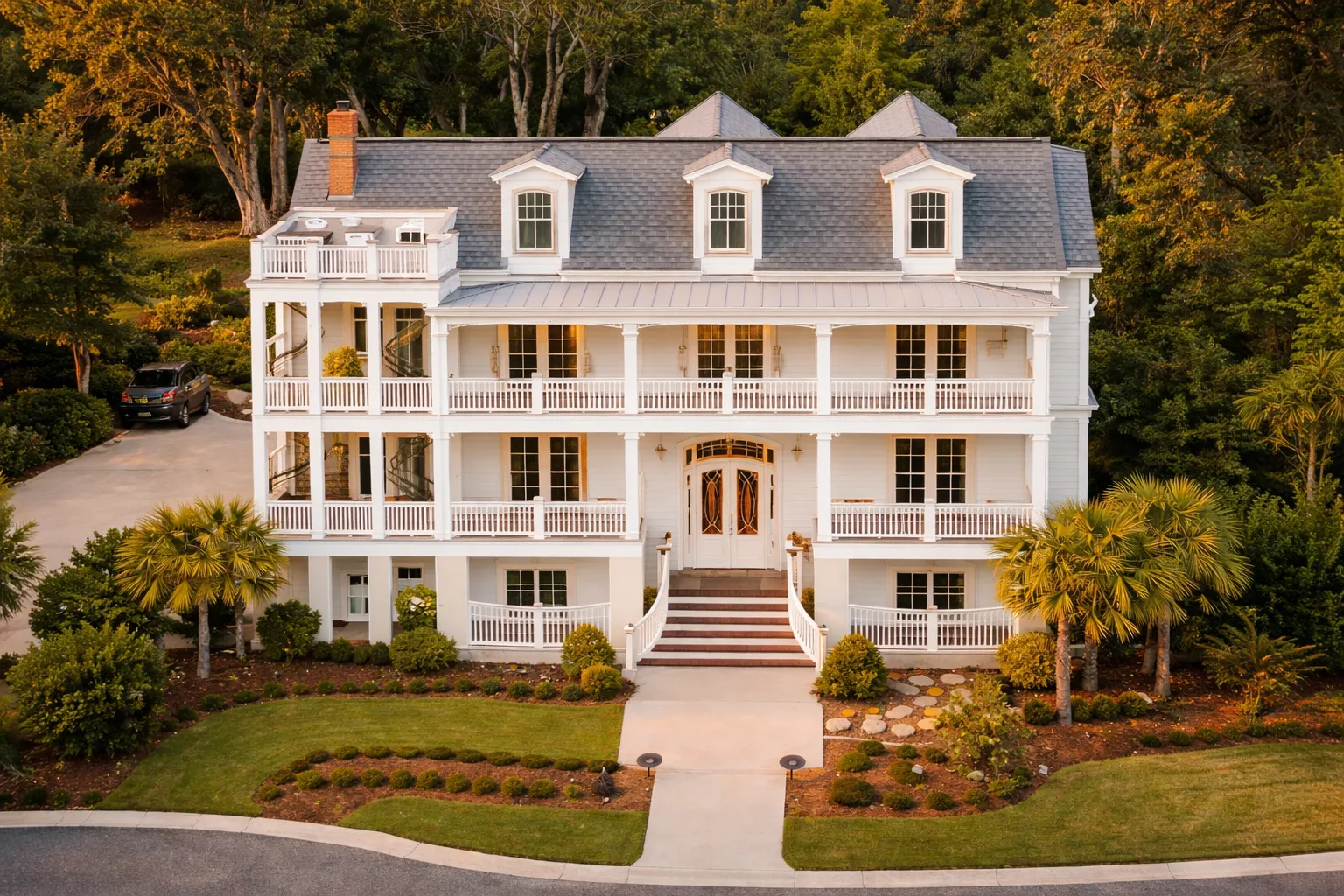Front exterior view of a Low Country Charleston-style coastal home featuring white clapboard siding, double stacked porches, symmetrical facade, and metal roof