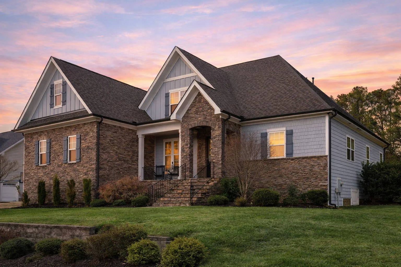 Front elevation of a New American style home featuring stone exterior, horizontal siding, black windows, and steep gabled roof
