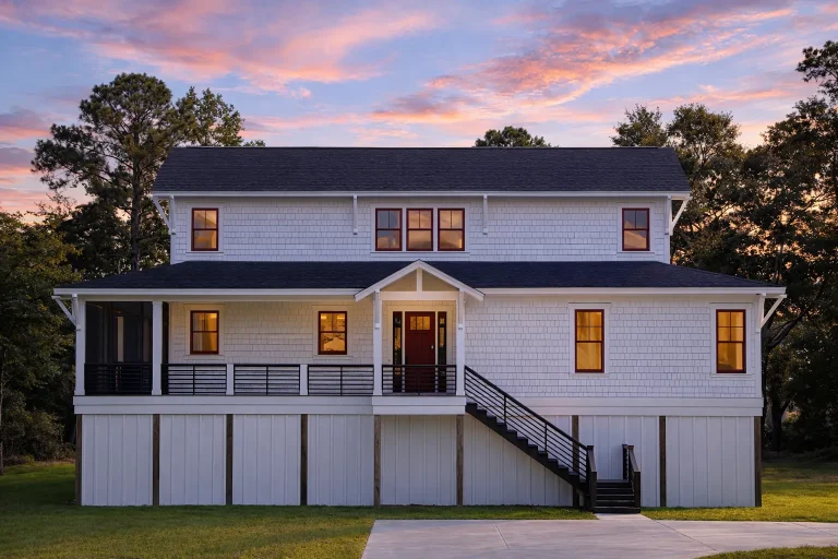 Front elevation of a Low Country coastal traditional home with horizontal siding, raised brick foundation, and covered front porch