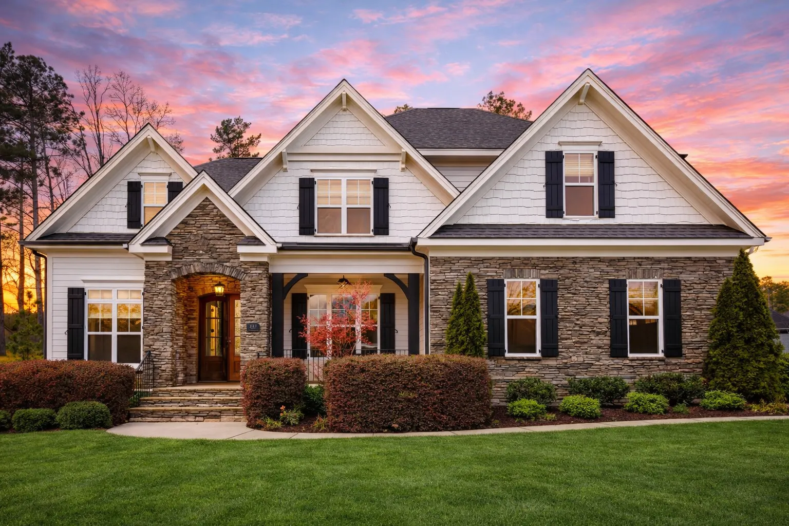 Front elevation of a New American modern traditional house featuring stone veneer, horizontal siding, symmetrical windows, and an attached garage