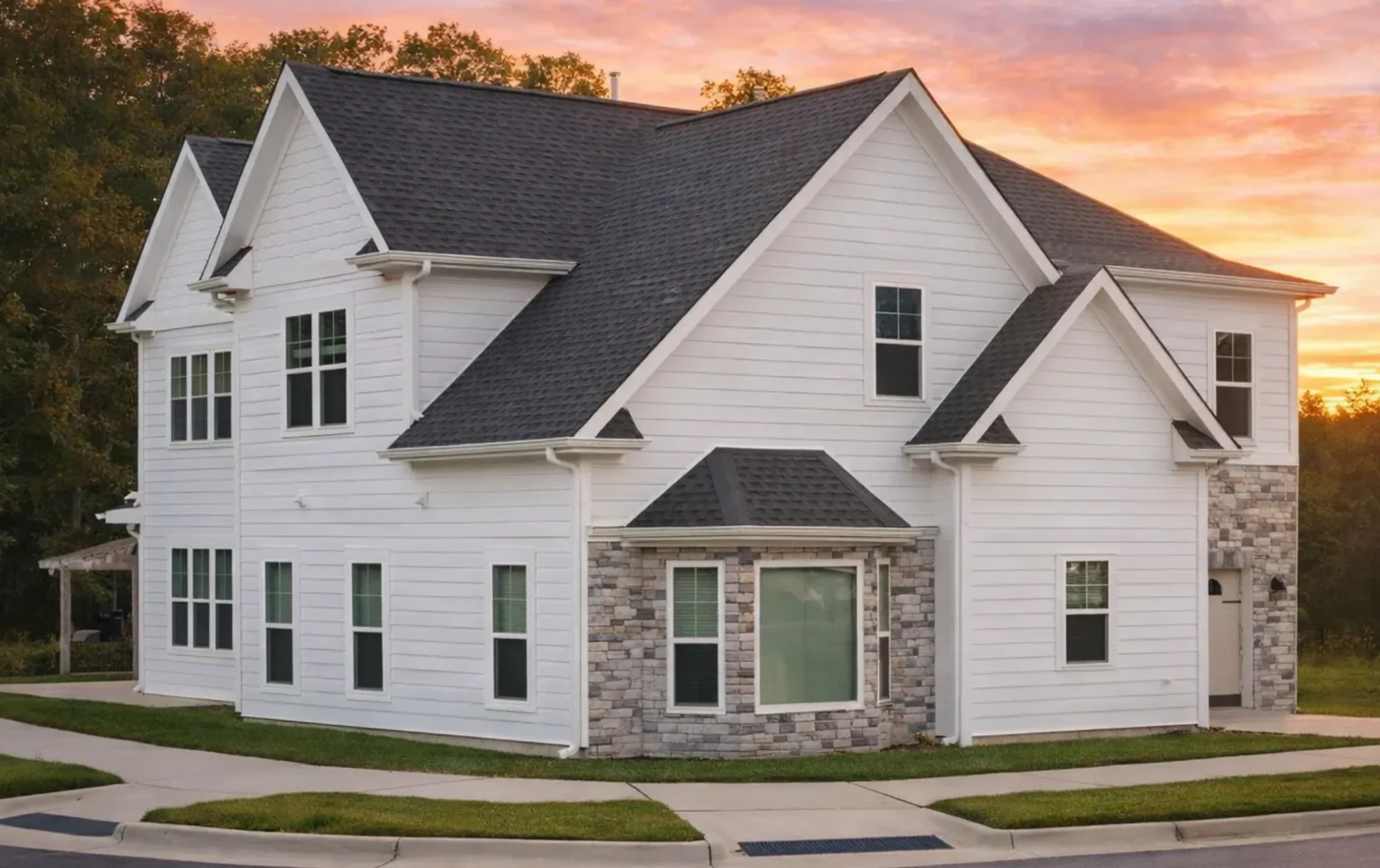 Front elevation of a Traditional Colonial style two-story home with white horizontal siding, shingle accents, stone base, and balanced window symmetry