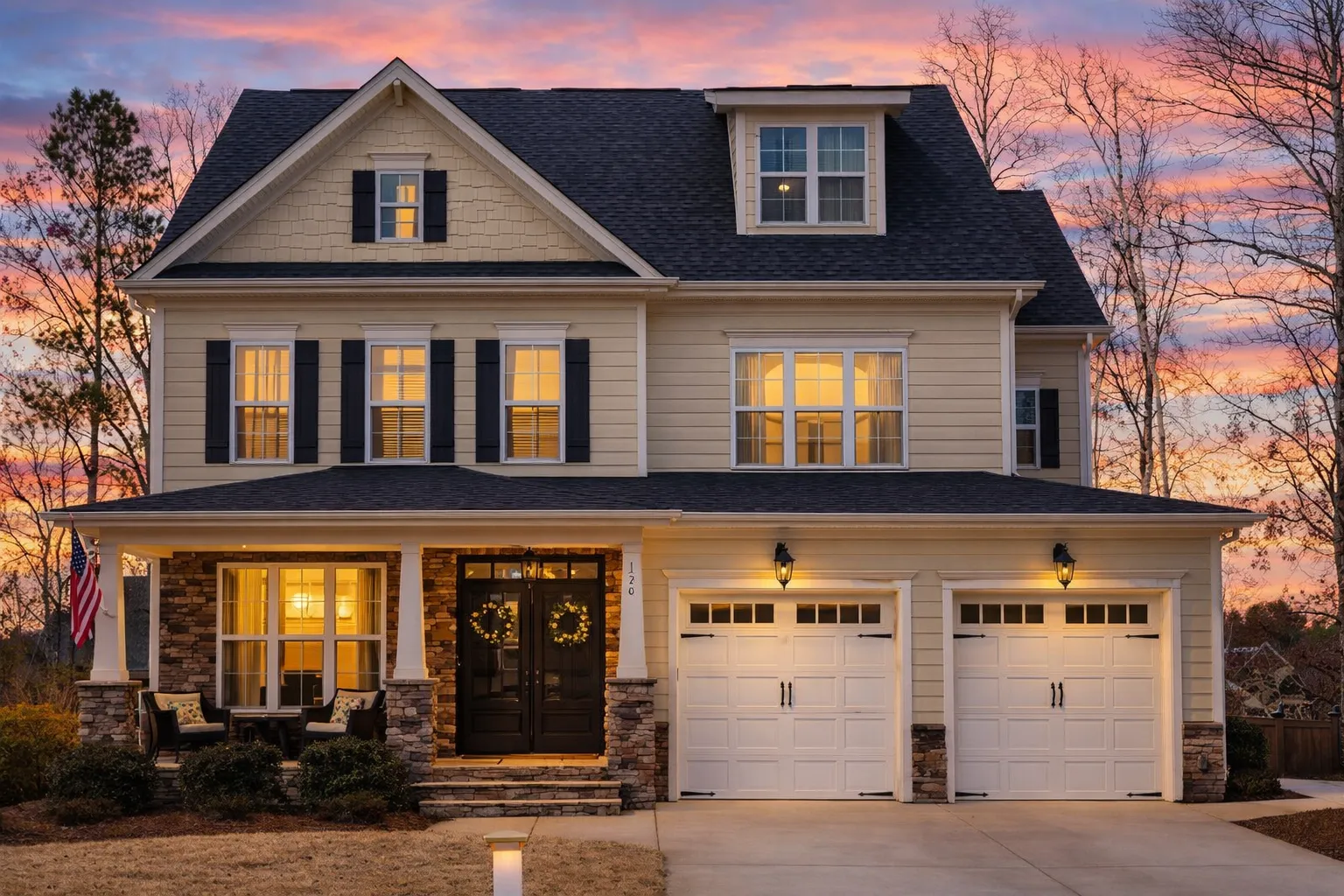 Front elevation of New American Traditional style home with horizontal lap siding, stone veneer base, gabled roof, and double garage