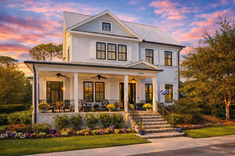 Front elevation of a Coastal Farmhouse style home featuring board and batten siding, metal roof accents, and a wide Low Country front porch