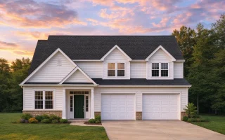 Front view of a Traditional Colonial style home featuring horizontal lap siding, stone accents, symmetrical windows, and a two-car garage