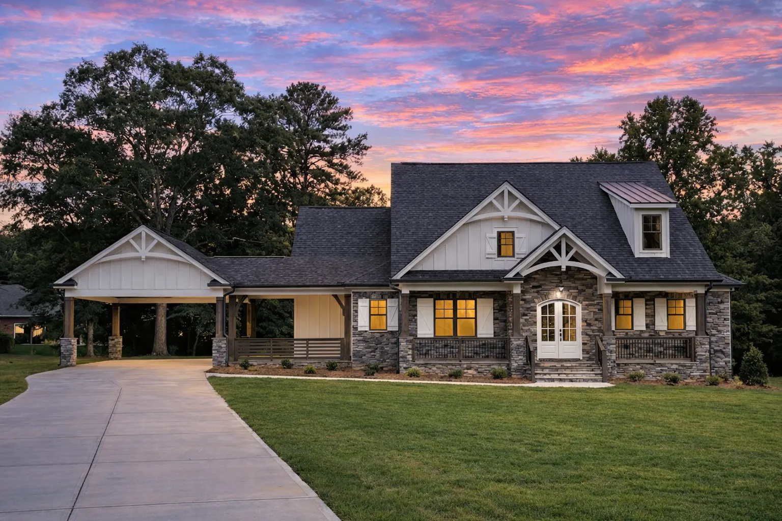 Front exterior of Craftsman style home with stone veneer, lap siding, shake gables, covered porch, and attached carport at sunset