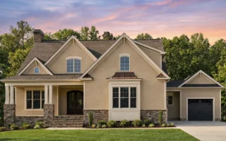 Front elevation of a New American Traditional style house featuring horizontal siding, stone veneer accents, gabled rooflines, and Craftsman-inspired details