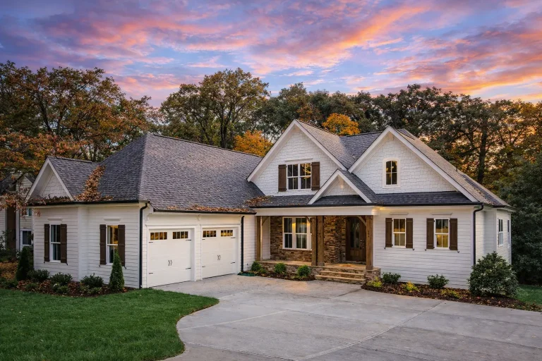 Front elevation of a Modern Farmhouse with board and batten siding, stone accents, gabled rooflines, and attached two-car garage