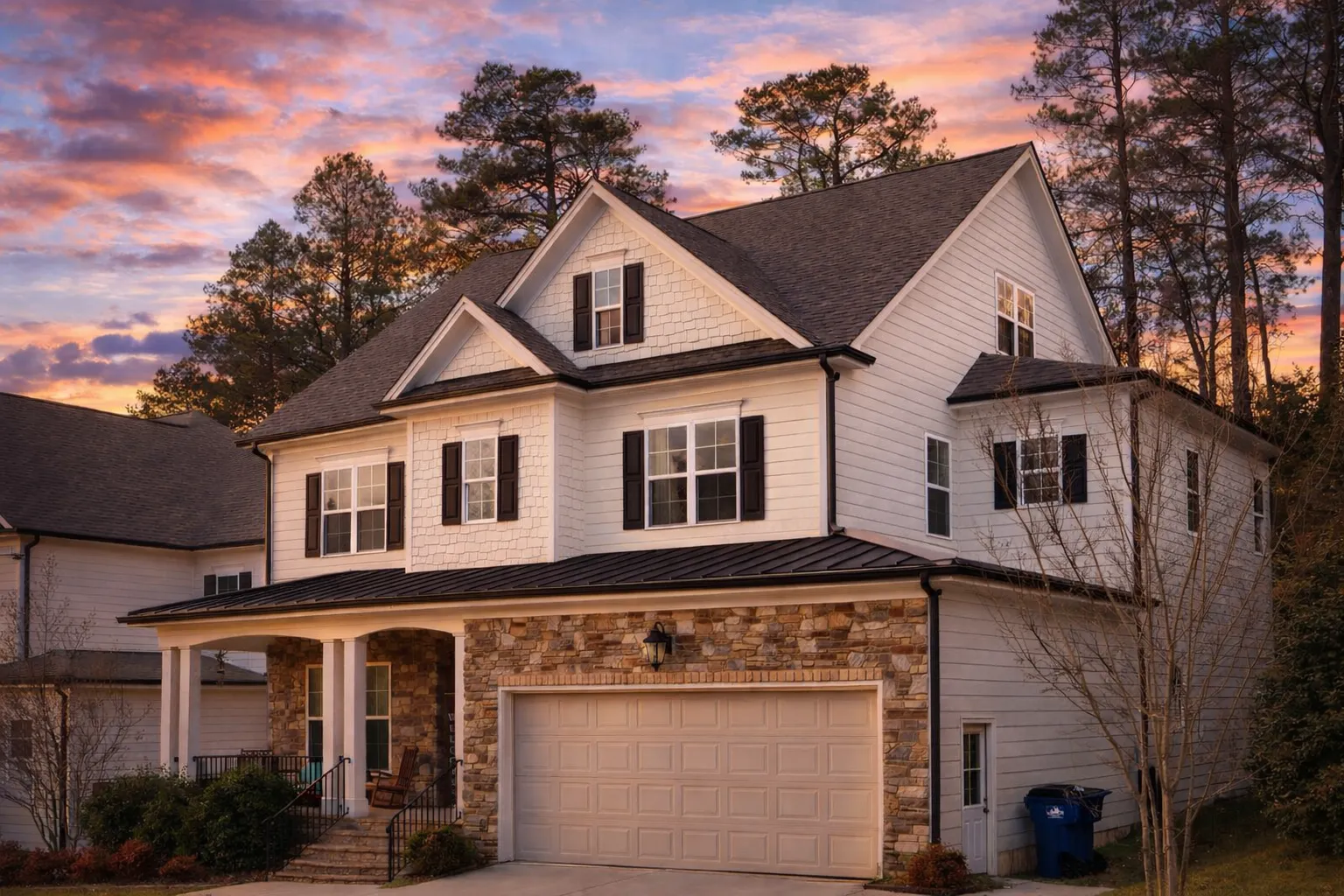 Front elevation of a New American style traditional home featuring horizontal siding, stone accents, black shutters, and a welcoming covered porch