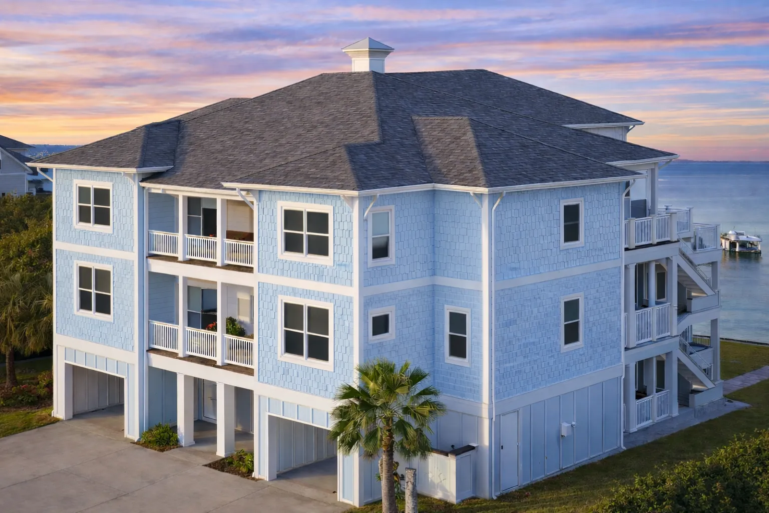 Front elevation of a Neo-Classical Georgian style home with smooth stucco exterior, arched garage openings, black shutters, and stacked balconies