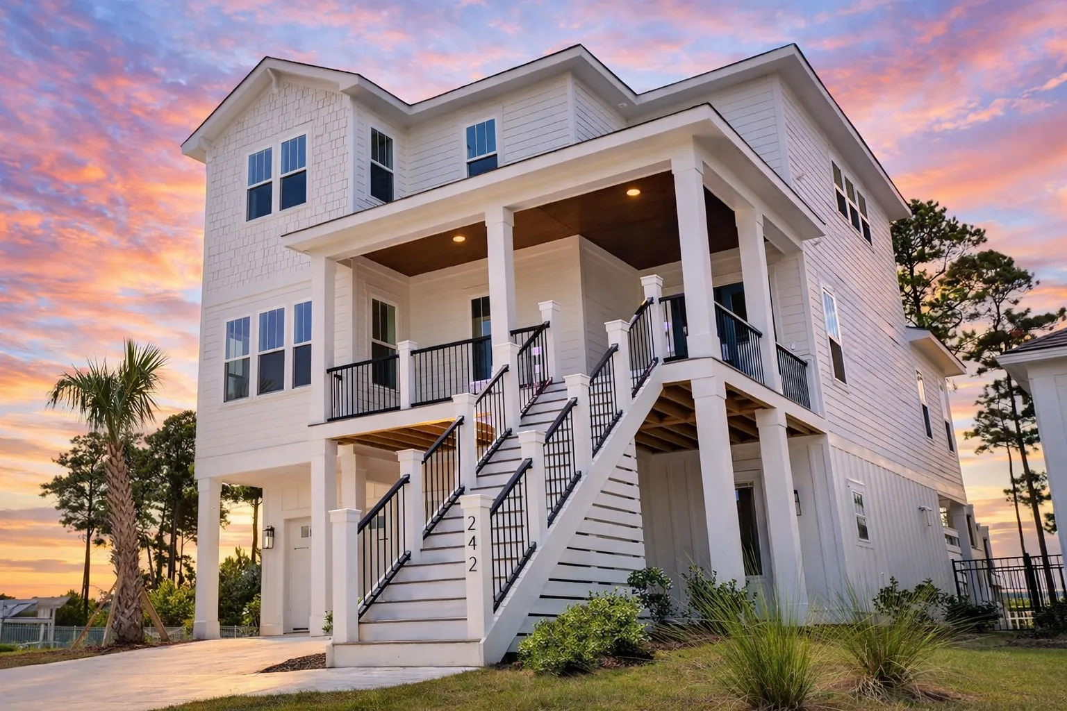 Front elevation of a Coastal Low Country style home with raised foundation, horizontal siding, shingle accents, double garage, and covered porch