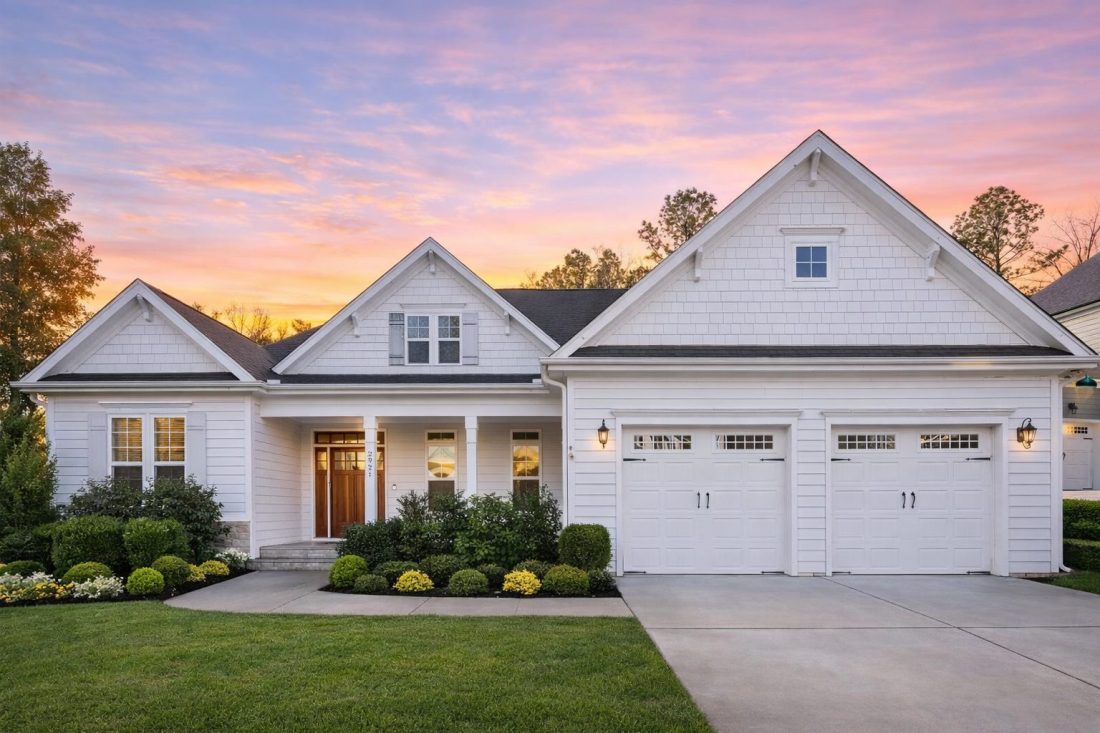 Front elevation of a New American Craftsman style house featuring horizontal siding, stone accents, gabled rooflines, and a covered front porch