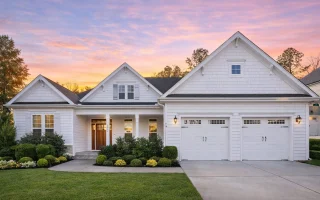 Front elevation of a New American Craftsman style house featuring horizontal siding, stone accents, gabled rooflines, and a covered front porch
