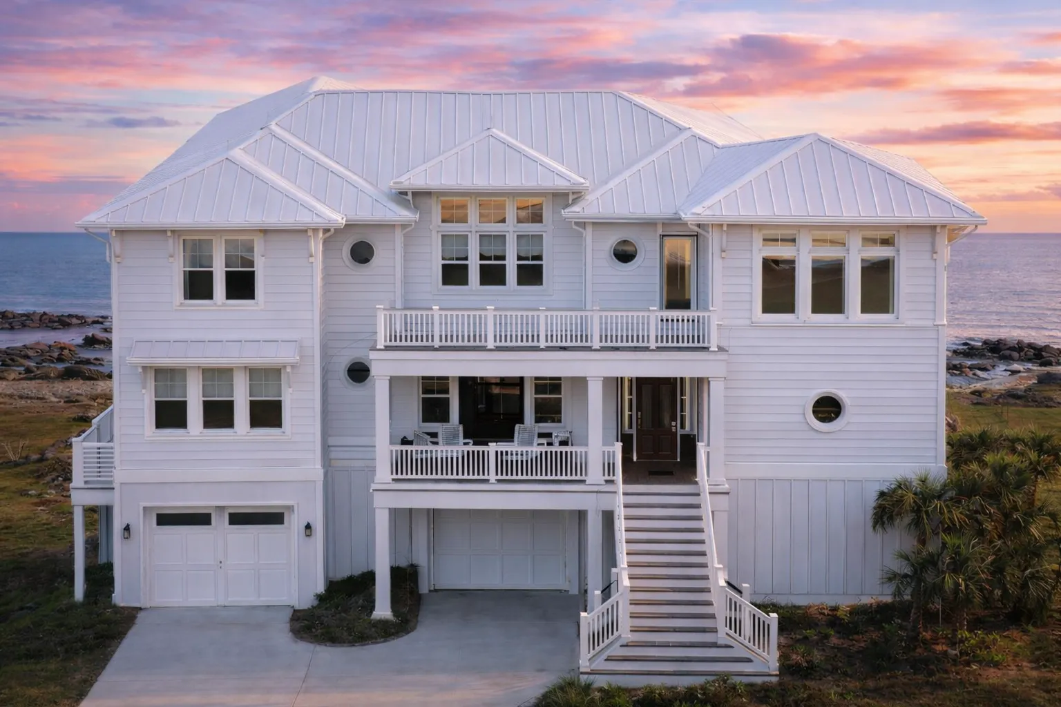 Front elevation of a Coastal Low Country style beach house with elevated design, lap siding, balconies, and ground-level garage