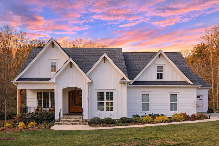 Front exterior of a New American cottage style home featuring blue lap siding, board and batten accents, gabled rooflines, and a welcoming covered porch