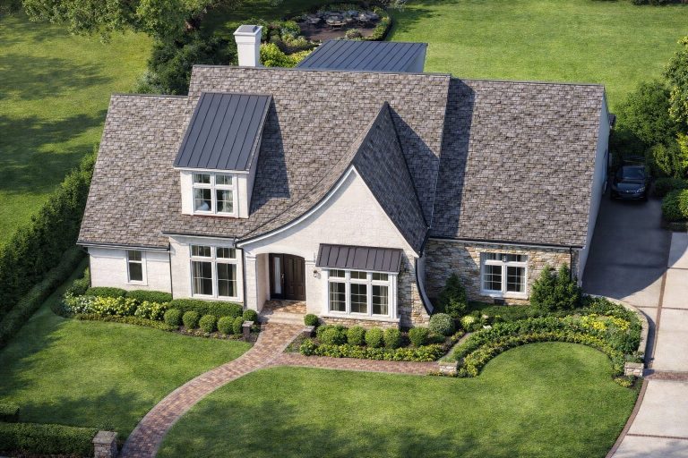 Front elevation of Modern Farmhouse ranch style home with white board and batten siding, stone accents, gabled roof, and covered entry porch