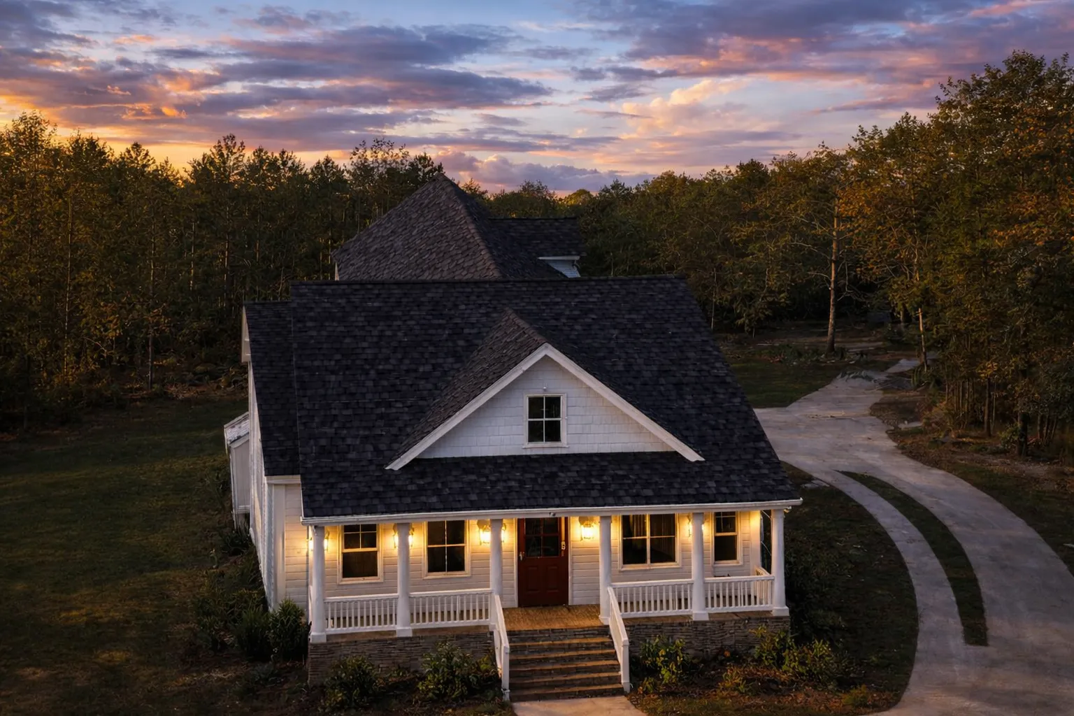 Front exterior view of a Cape Cod coastal cottage house with blue siding, brick foundation, covered porch, and symmetrical traditional design