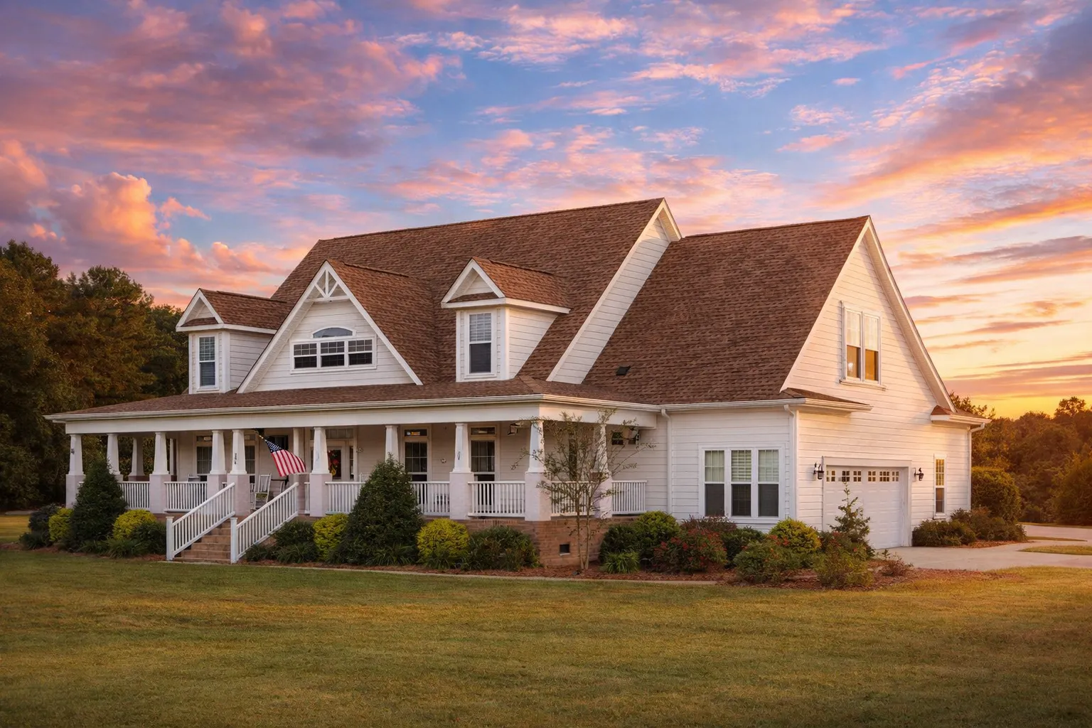 Front exterior of Southern Farmhouse style home with white horizontal lap siding, dormers, gabled roof, and wraparound covered porch