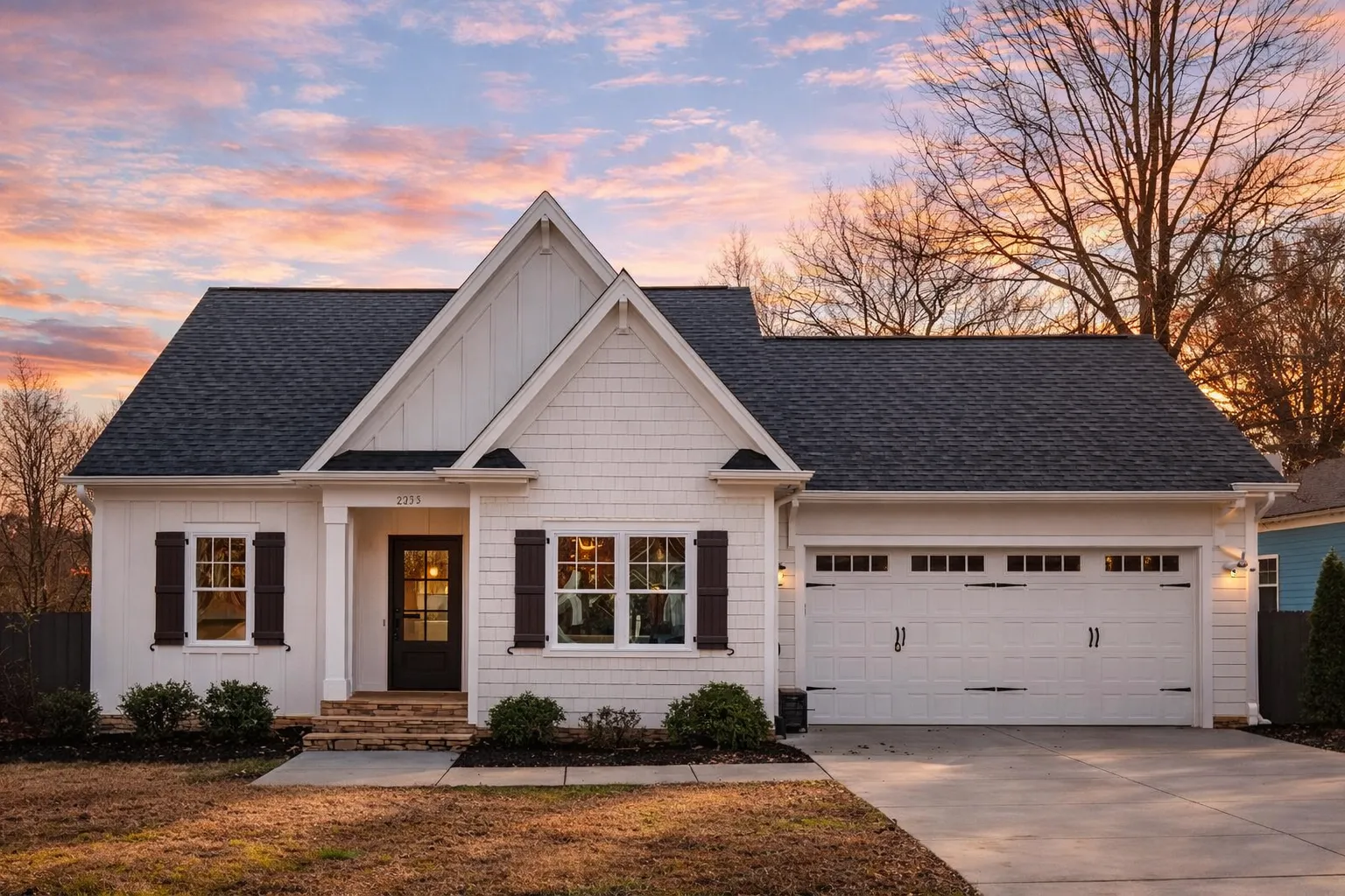 Front elevation of a Traditional Ranch suburban home featuring stone accents, horizontal siding, gabled rooflines, and a two-car garage