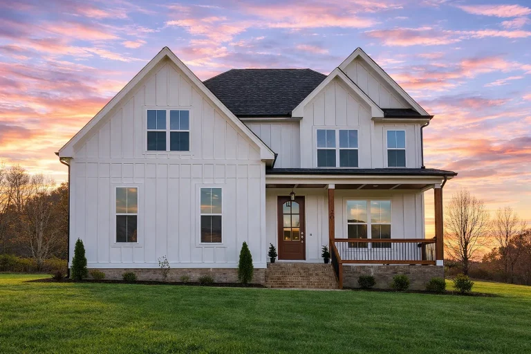 Front elevation of a modern farmhouse style home with white board and batten exterior, stone foundation accents, steep gable roof, and symmetrical windows