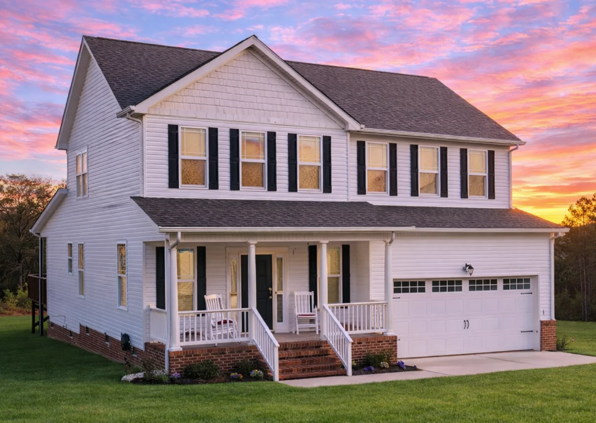 Front view of a Traditional Colonial style home with blue shutters, gray siding, and brick foundation accents beneath a welcoming covered porch.