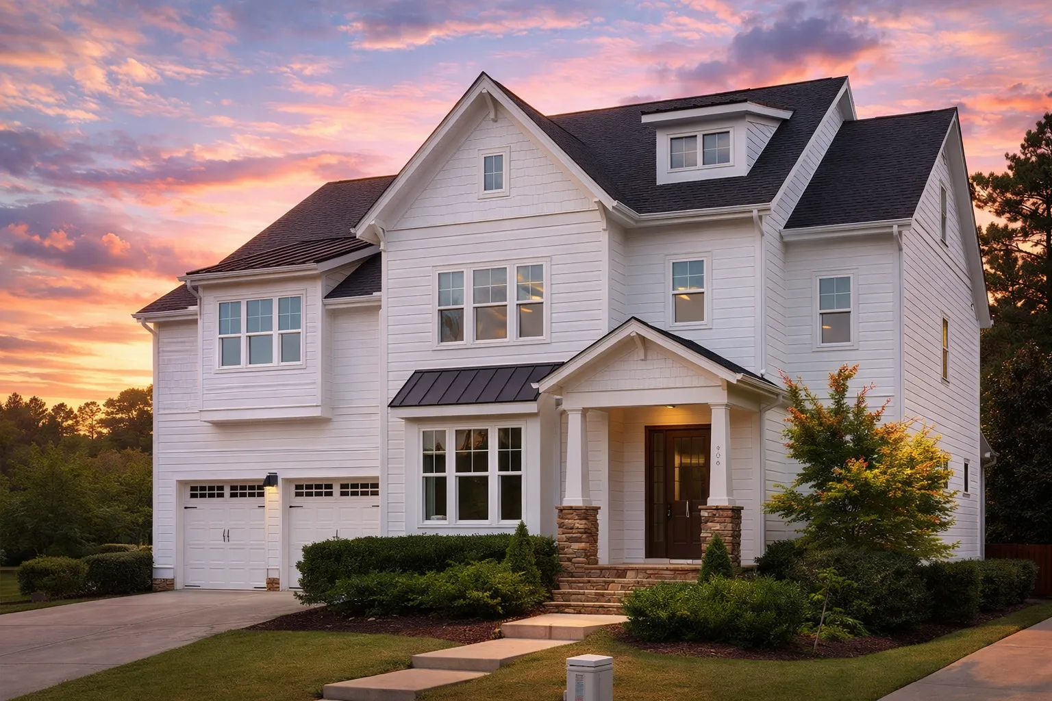 Front elevation of a Shingle Style New American home with horizontal siding, stone porch columns, steep gabled rooflines, and covered front entry