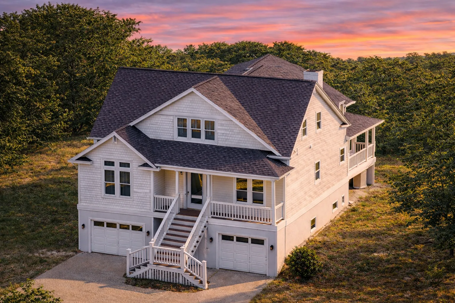 Front elevation of a Modern Farmhouse style home with horizontal siding, stone foundation, black-framed windows, and dual front-entry garages beneath an elevated porch