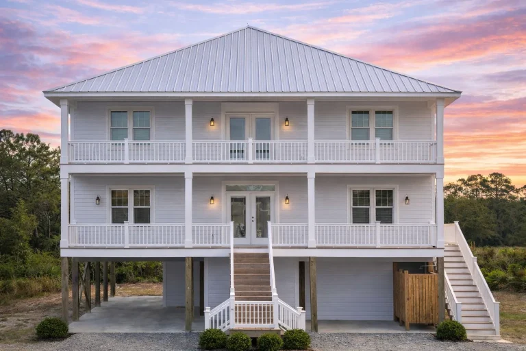 Front elevation of Low Country Coastal Traditional home with double stacked porches, white horizontal lap siding, and elevated foundation