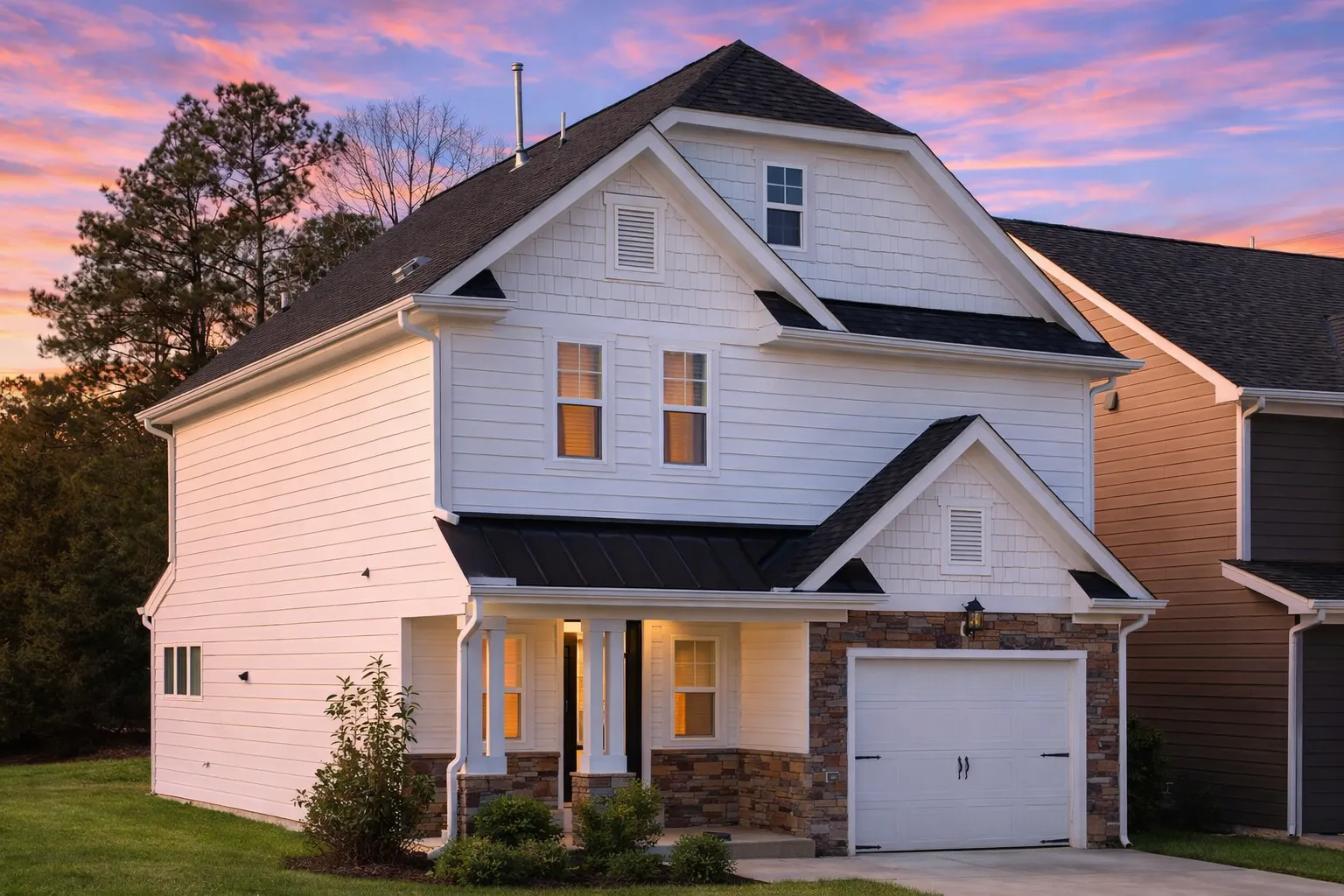 Front view of a Traditional New American style house featuring stone and horizontal siding with shingle accents, black shutters, and a one-car garage