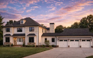 Front exterior of a Traditional Colonial style home featuring brick facade, horizontal siding, symmetrical windows, gabled rooflines, and a side-entry garage