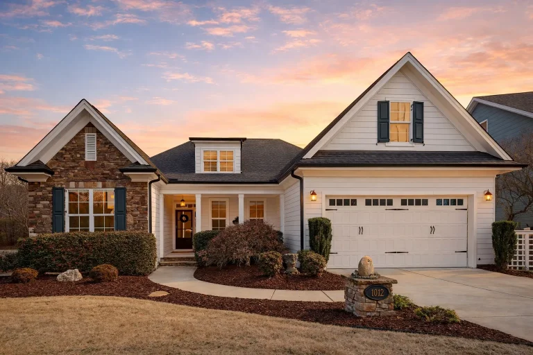 Front view of a Traditional Colonial style home featuring stone and siding exterior, gabled rooflines, and a welcoming front porch entry