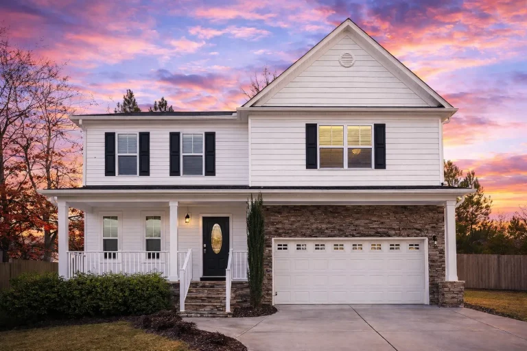 Front view of a Traditional Colonial style home featuring a New American influence with horizontal siding, stone accents, and symmetrical windows.