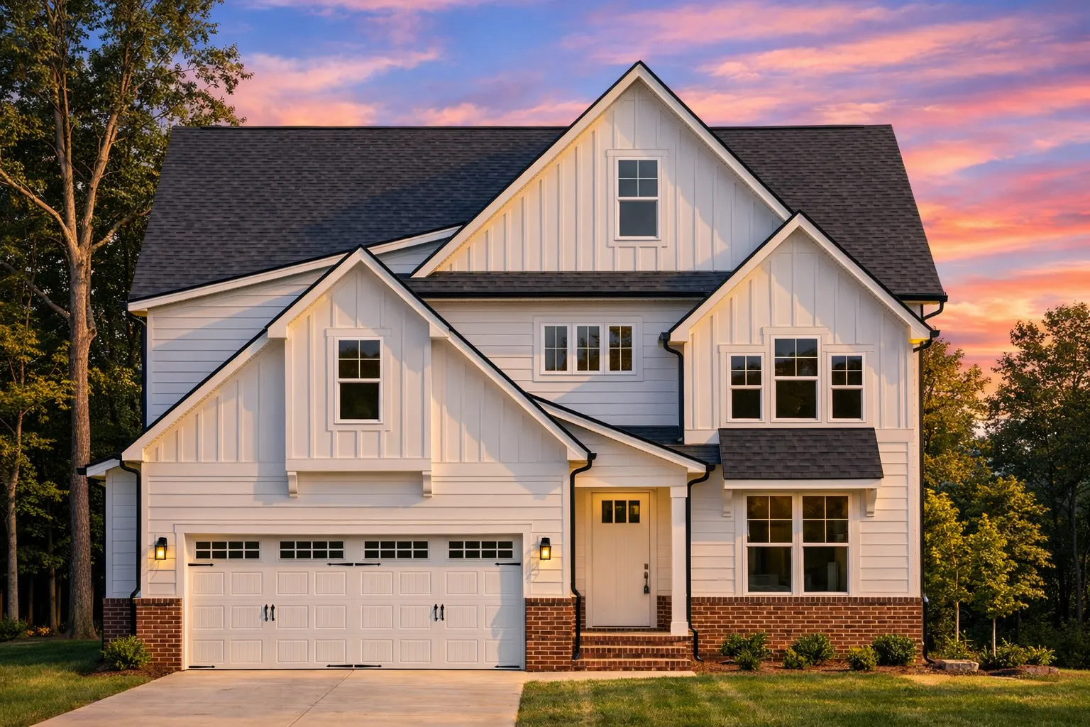 Front elevation of Modern Farmhouse home with white board and batten siding, brick base, gabled rooflines, and attached two-car garage