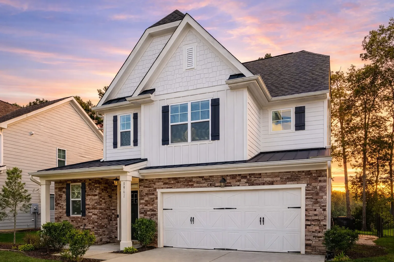 Front exterior view of a New American Traditional Craftsman home featuring brick, board and batten siding, layered gables, and a two-car garage