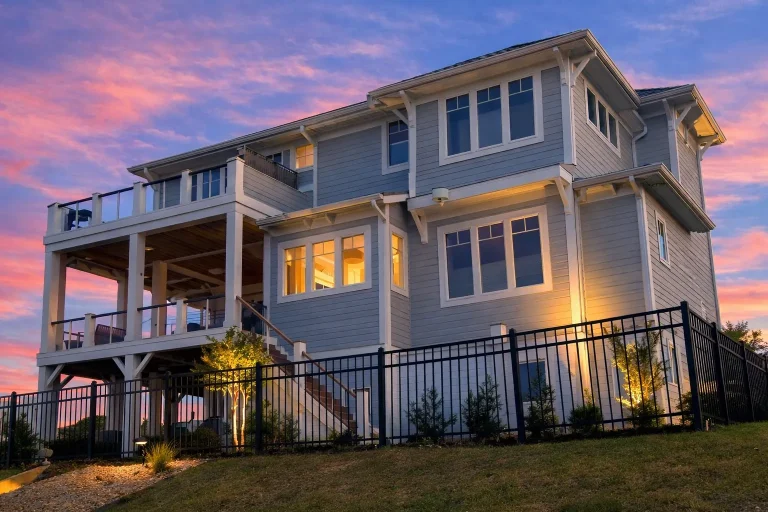 Front elevation of a Coastal Traditional Southern home with lap siding, stone accents, double porches, and elevated garage design