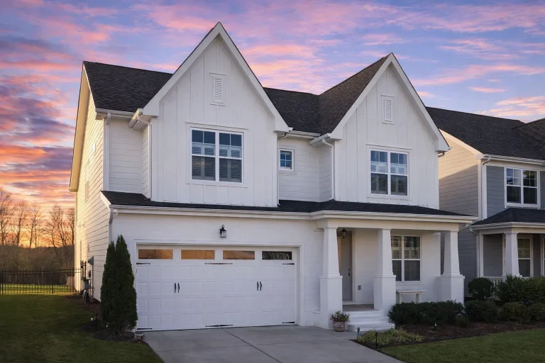 Front elevation of a New American traditional suburban house featuring horizontal siding, symmetrical gables, shuttered windows, and an attached two-car garage