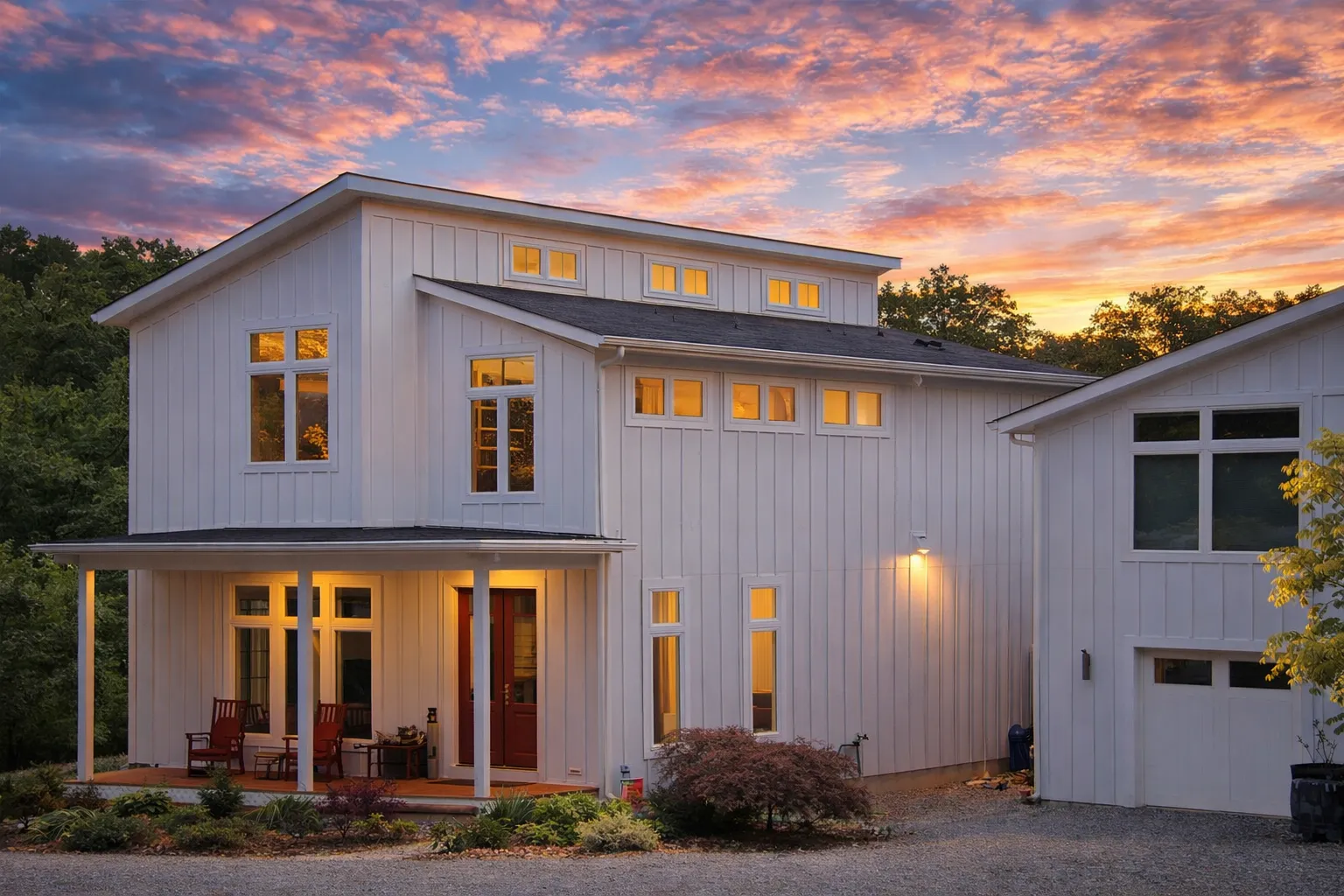 Front elevation of a modern farmhouse style home featuring white board and batten siding, stone base, black windows, and a covered porch