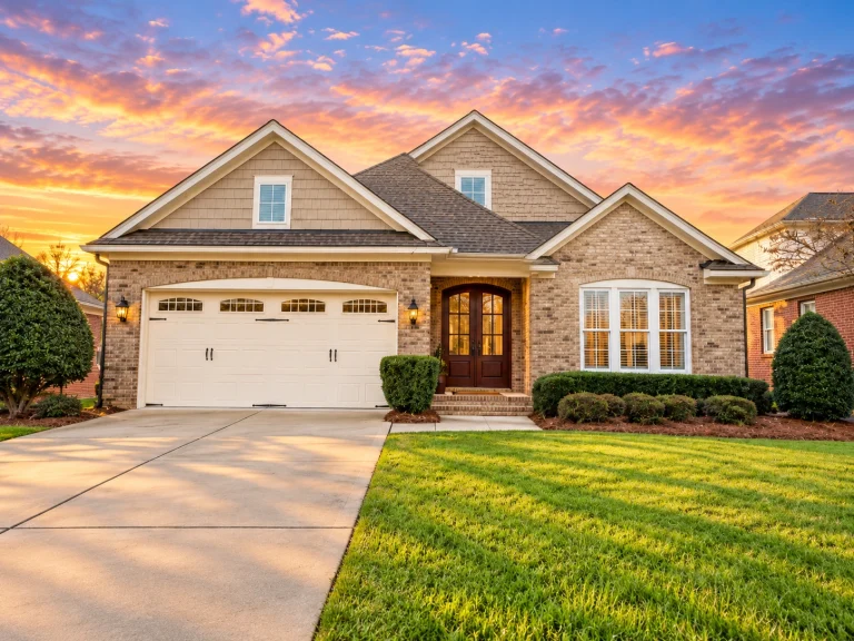 Front elevation of a traditional suburban brick home with symmetrical gables, arched entryway, and attached two-car garage