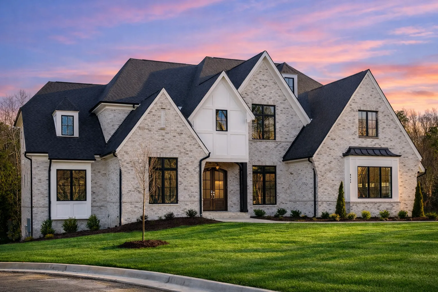 Front exterior of a New American Modern Traditional home featuring painted brick, stone accents, steep gables, and symmetrical architecture