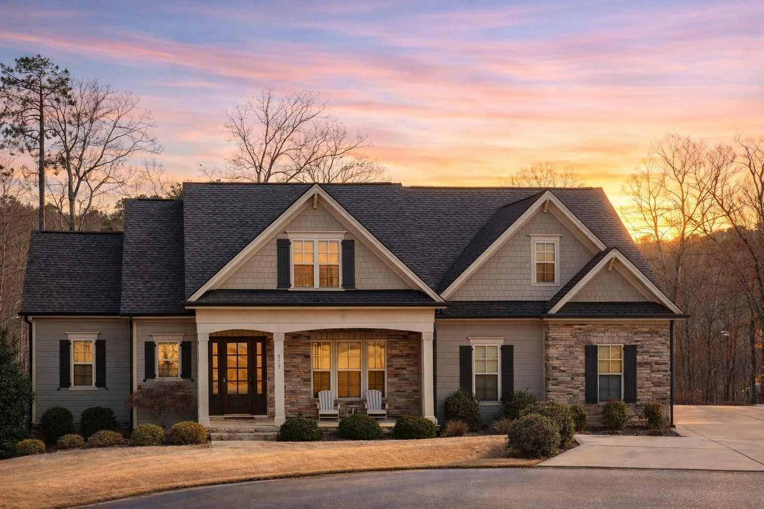 Front elevation of a New American Traditional style house featuring horizontal siding, stone accents, gabled rooflines, and an attached garage