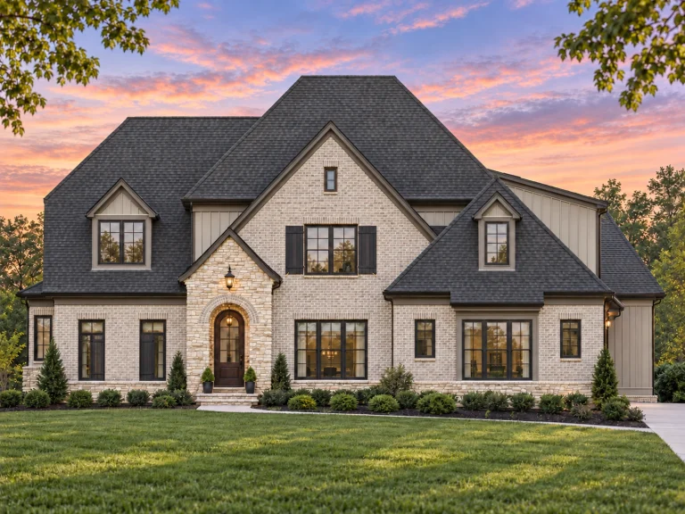 Front exterior of a New American Traditional house with painted brick, stone arched entry, board-and-batten gables, and steep shingle roof