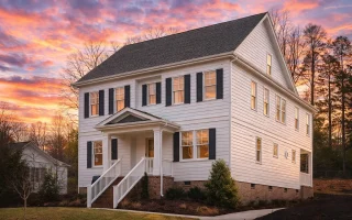 Front elevation of a Colonial style home with symmetrical windows, horizontal siding, shingle upper exterior, and centered entry porch