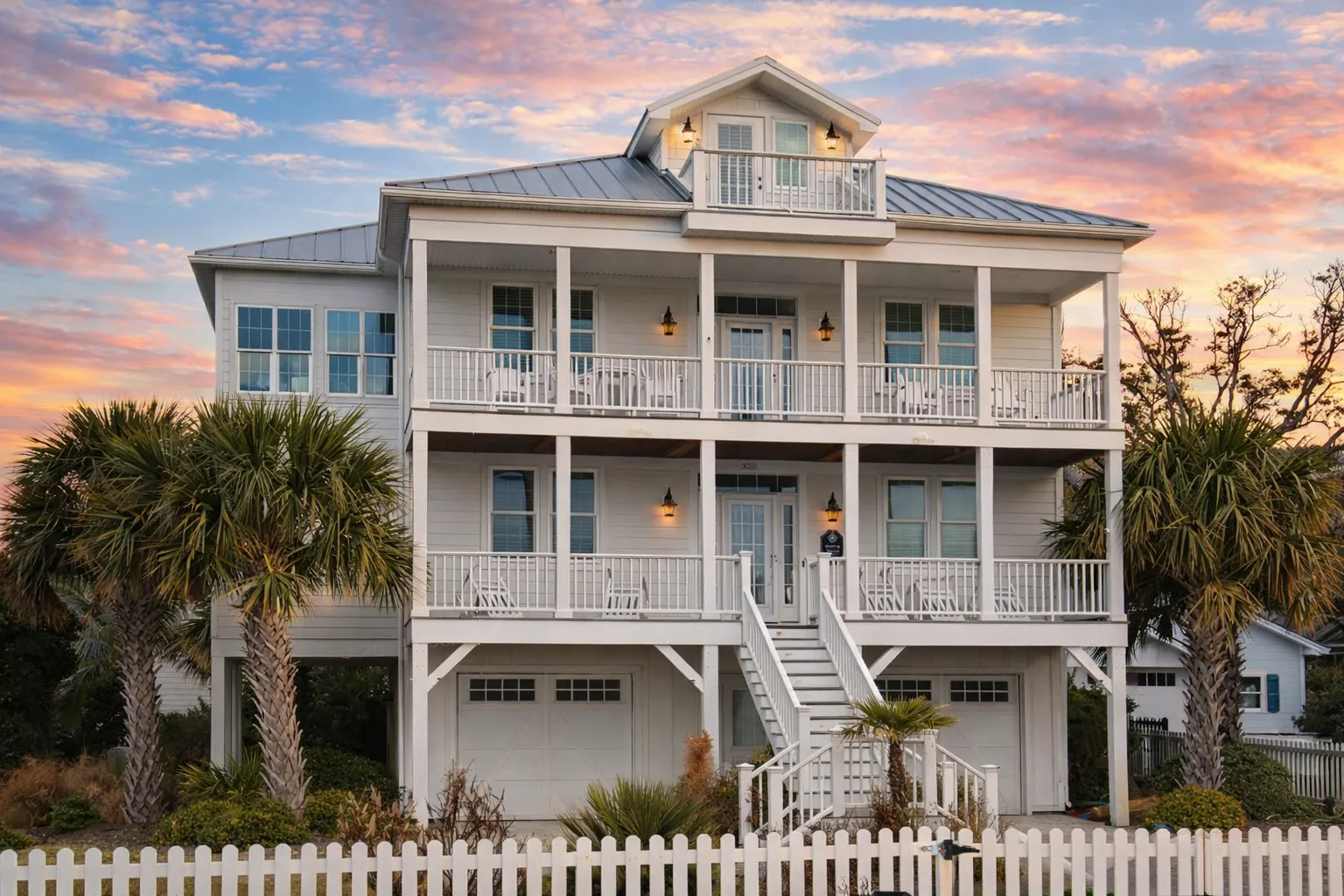 House Plans 19 Front exterior view of a coastal beach house with elevated design, double stacked porches, white siding, and standing seam metal roof