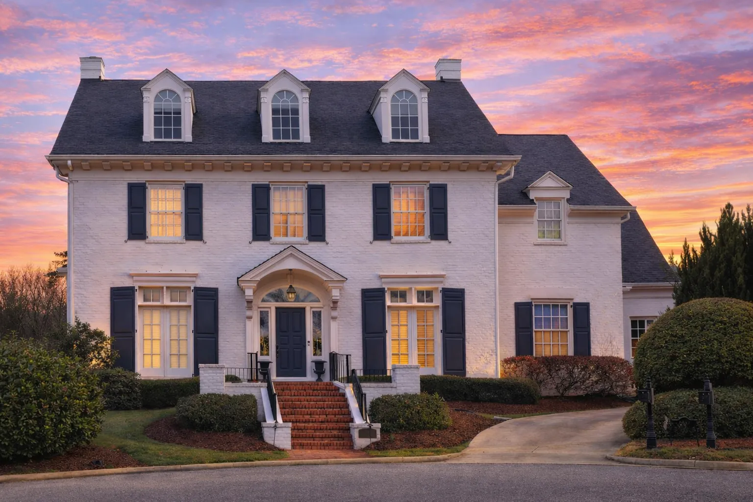 Front elevation of a Georgian Colonial style home featuring a full brick exterior, dormer windows, black shutters, and a formal central entry