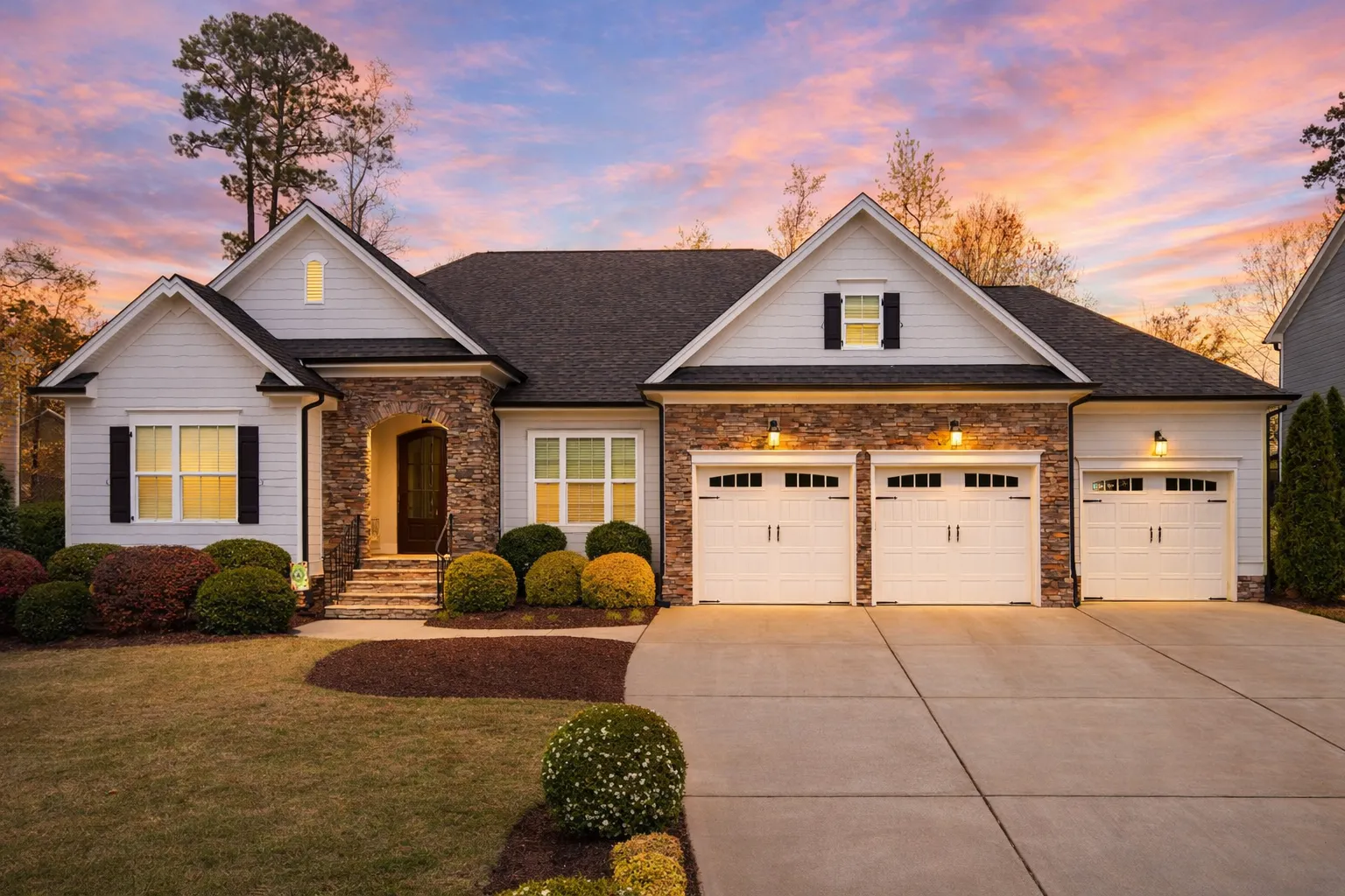 Front elevation of a New American modern traditional house with stone accents, horizontal siding, and a three-car garage