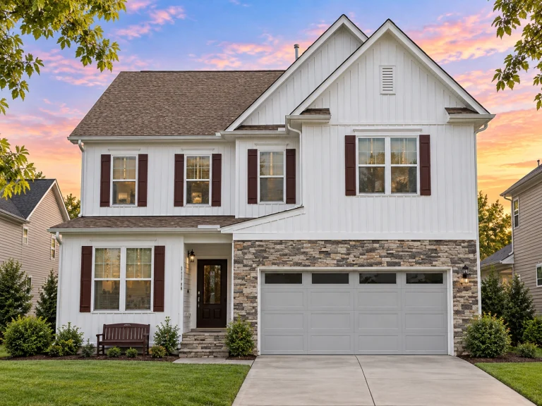 Front elevation of a New American coastal traditional home featuring horizontal siding, stone garage base, and an upper-level balcony
