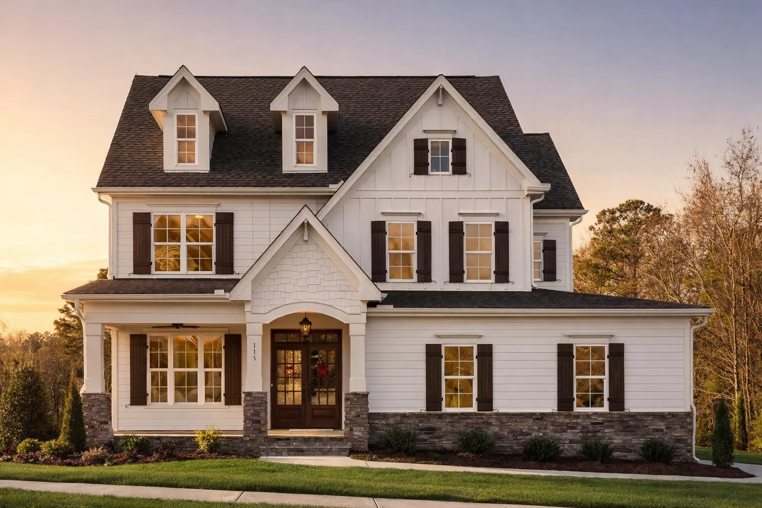 Front exterior view of a Modern Farmhouse and New American style home featuring board and batten siding, stone foundation, black shutters, and a welcoming covered porch