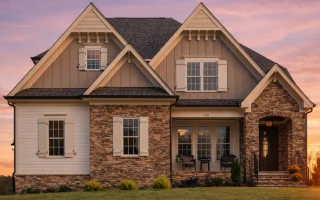 Front elevation of a New American farmhouse-style home featuring board and batten siding, stone accents, black shutters, and a welcoming covered entry