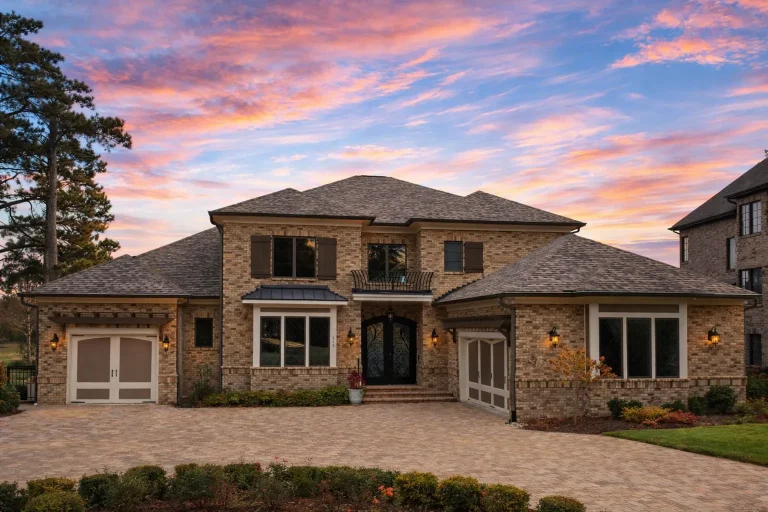 Front elevation of a Traditional New American style home featuring a brick exterior, symmetrical façade, arched entry, and refined suburban architecture